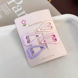 Close-up of four heart-shaped pastel hair clips on a card display with soft background