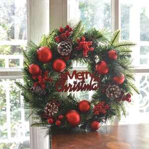 Weihnachtskranz mit roten Beeren Zapfen und Frohe Weihnachten Schild auf Holztisch