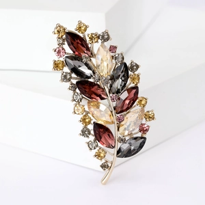 Detailed view of colorful crystal leaf brooch with a gold-tone metallic setting
