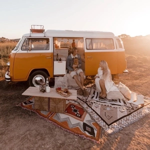 Bohemian outdoor camping blanket with geometric patterns and white tassels on a van