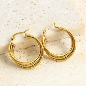 Three-layer C-shaped layered gold earrings in stainless steel on a stone texture background