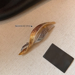 Detail of interlocking leaf brooch in gold and silver finish with sparkling zircons