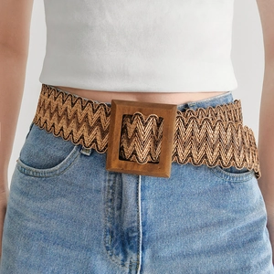 Detail of woven straw belt with square wooden buckle on denim jeans and white top