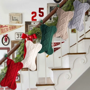 Detail of bone-shaped cable knit Christmas stockings hanging on staircase with decor