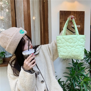 Quilted floral handbag in light green shown in an outdoor lifestyle setting with model