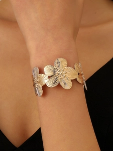 Detail of gold floral cuff bracelet with textured petals worn on a model's wrist