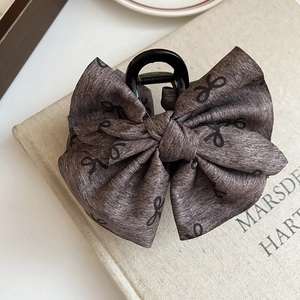 Detail of grey fabric bow hair claw clip with vintage pattern and black base grip