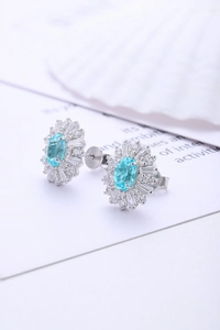 Dettaglio macro di orecchini a lobo in argento S925 con gemma blu e design a girasole