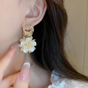 Gros plan d'un mannequin portant des boucles d'oreilles rétro dorées et fleurs acryliques