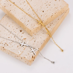 Sleek gold and silver stainless steel cross tassel necklaces on beige stone blocks