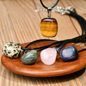 Minimalist irregular natural stone pendant necklaces on a wooden tray with black cord