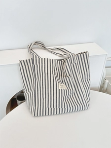 Blue and white striped canvas tote bag with decorative label on a minimalist table