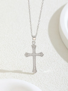 Macro view of silver cross necklace featuring micro-set zircon and vintage engravings