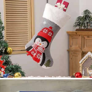 Detail of grey Christmas stocking with red knit penguin and snowy tree motifs