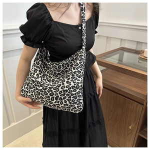 Leopard print canvas tote bag shown by model in a stylish indoor setting