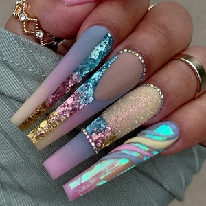 Detail of long ballerina fake nails with matte blue finish, glitter, and rhinestones