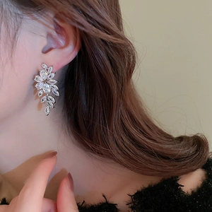 Close-up of elegant silver leaf tassel earrings with zircon crystals on a model's ear