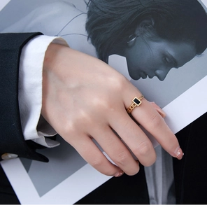 Close-up of golden chain band ring with black rectangular enamel on a fashion magazine