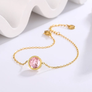 Detail view of a 18k gold plated bracelet featuring a round pink crystal in bezel setting