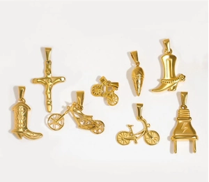 Macro detail of assorted golden charms including cowboy boots, crosses and motorcycles