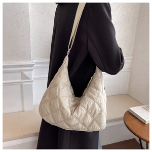 Close-up of beige quilted crossbody bag with adjustable strap on a minimalist model