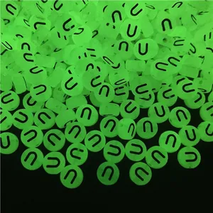 Close-up of luminous green round acrylic beads with letter U for DIY jewelry making