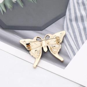 Detailed back view of gold butterfly brooch showing the metal pin buckle and texture