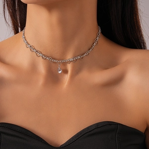 Gros plan d'un choker en dentelle argentée avec zircons et pendentif goutte sur la clavicule