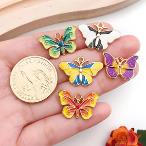 Detail of five colorful alloy butterfly pendants with a coin for size reference