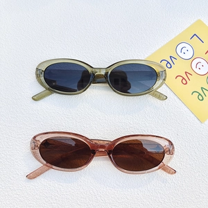 Occhiali da sole ovali UV400 con montatura verde oliva e ambra su sfondo bianco materico