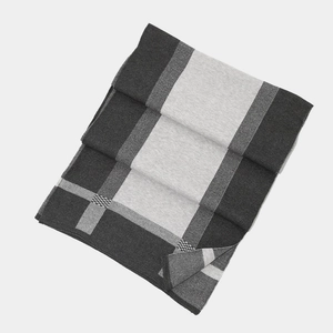Detailed close-up of thick winter knit scarf featuring grey and black patchwork design