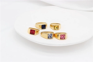 Close-up of five gold-plated signet rings with square gemstones in assorted colors