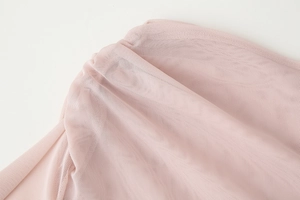 Close-up of light pink mesh fabric detail with delicate ruffle seams and soft texture