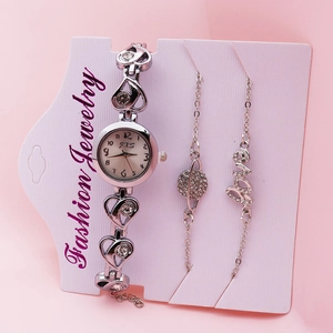 Detailed view of elegant silver women's quartz watch and bracelet set on a soft pink background