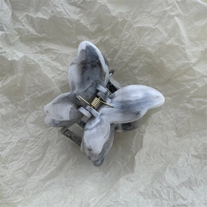 Macro detail of butterfly hair claw clip with black and white marble acetate texture