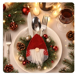 Christmas gnome cutlery holder on dinner plate with festive pine cones and warm lights