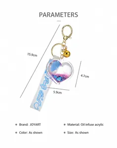 Detailed view of heart shaped oil-filled acrylic quicksand keychain with bell and strap