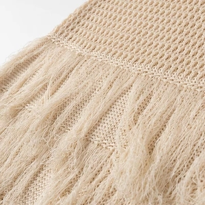 Gros plan détaillé de la texture en maille crochet beige et des franges sur la robe