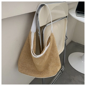 Detail of khaki woven straw bag with white shoulder strap on a chair for beach travel