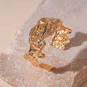 Macro shot of gold cuff bracelet featuring irregular hammered liquid metal textures