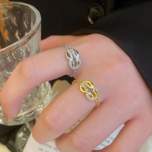 Close-up of gold and silver knot chain rings with zircon stones on a model hand
