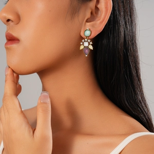 Gros plan de boucles d'oreilles pendantes dorées avec pierres précieuses sur un mannequin