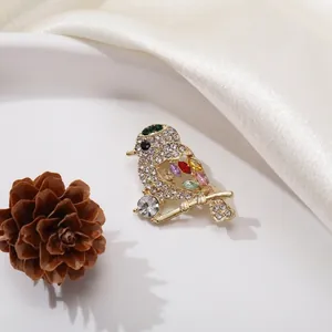 Elegant gold bird brooch with sparkling rhinestones and colorful gemstones on a branch