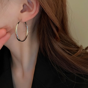 Close-up of polished silver hoop earrings worn by a model for a minimalist fashion look