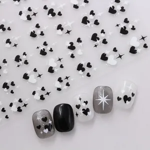 Detail view of black and white heart nail stickers with star motifs on false nails