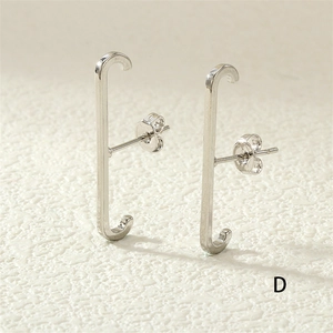 Close-up of J-shaped silver stud earrings with sparkling rhinestones on white texture