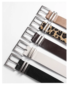 Flat lay of multiple leopard print and solid faux leather belts with silver buckles