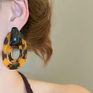 Detail of tortoiseshell acrylic resin earrings on model showing vintage amber texture