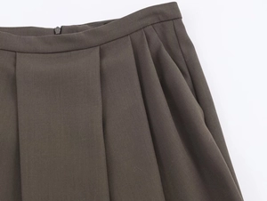 Detail of dark brown pleated skirt featuring twill fabric texture and hidden zipper closure