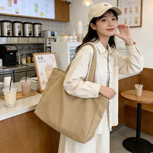 Minimalist large canvas tote bag shown in a lifestyle setting at a cozy cafe shop